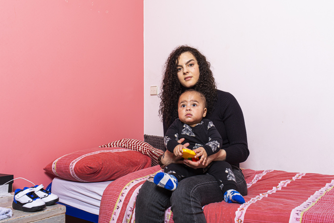 Jonge vrouw met haar zoontje zit op een bed in de opvang voor tienermoeders van het Leger des Heils   
