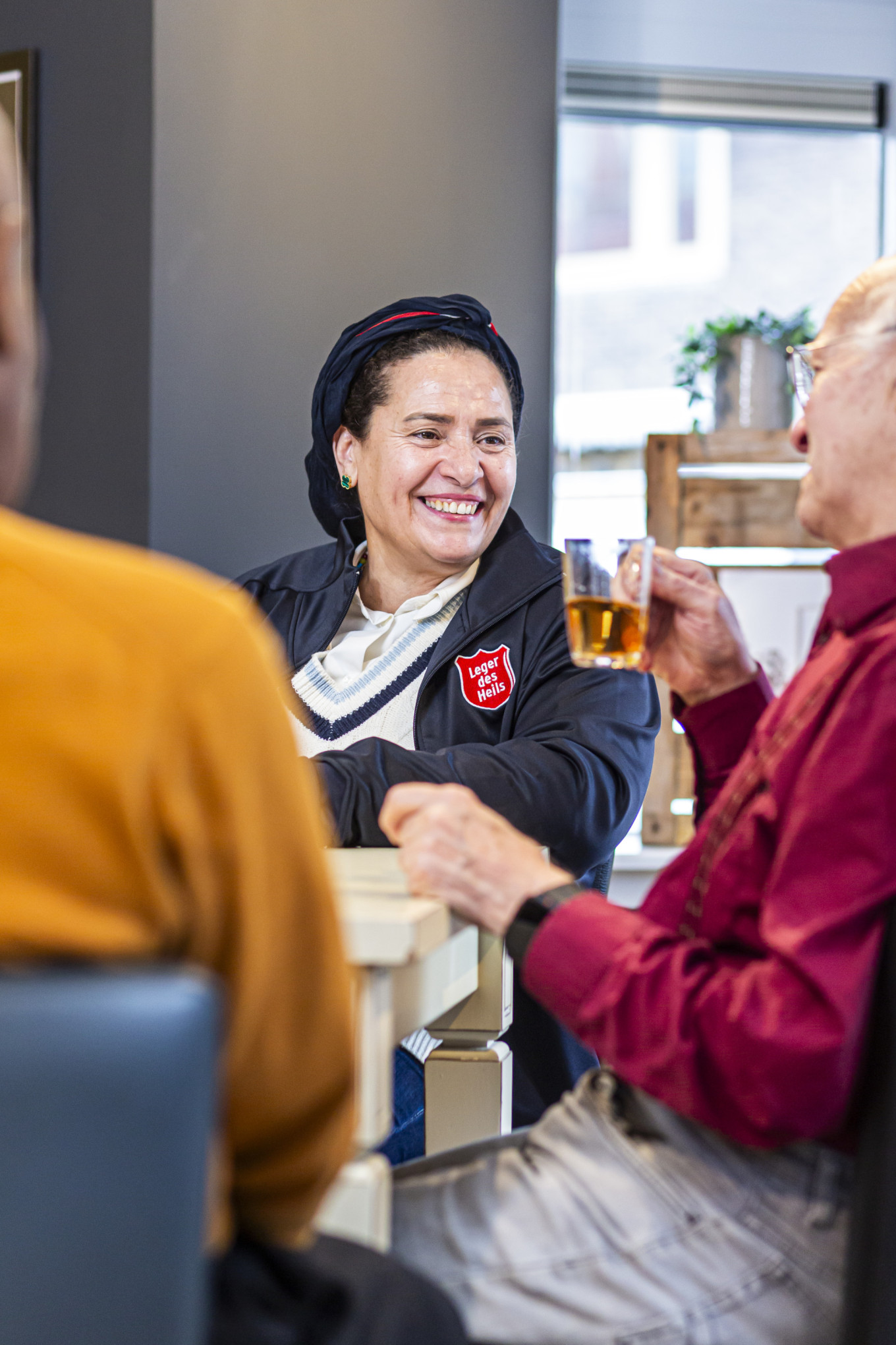 Vrijwilligster Asmaa in gesprek met bezoekers in de buurthuiskamer  Folkert Koelewijn