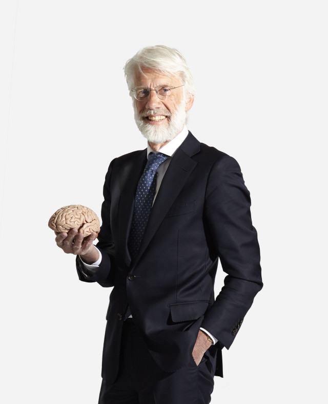 Neuropsycholoog Erik Scherder staat rechtop met een model van hersenen in zijn rechterhand