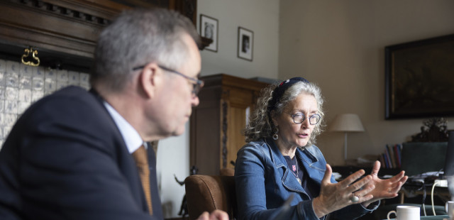 Burgemeester Wienen en Ineke van Buren in discussie over mensenhandel aan tafel in woonkamer