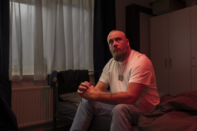 Man zittend in kamer kijkt omhoog naar iemand die binnen komt lopen